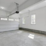This image depicts a clean, bright garage with dual overhead doors half open, providing an inviting space with ample natural light filtering through the windows.